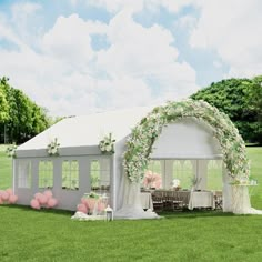 a white tent set up in the middle of a field with balloons and flowers on it