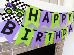 a birthday banner with monster trucks and checkered flags hanging from a fireplace mantel