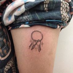 a woman's thigh with a small tattoo of a key and feathers on it