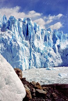 a man standing on top of a pile of snow next to a glacier