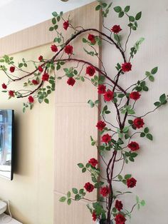 a tv mounted to the side of a wall next to a plant with red flowers on it