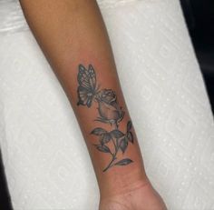 a woman's arm with a butterfly and rose tattoo on the left side of her wrist