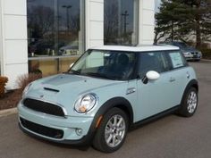 a light blue mini cooper parked in front of a building with two cars behind it