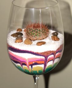 a wine glass with some rocks and a cactus in it