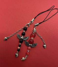 a cross with beads and charms on a red surface, next to a black cord