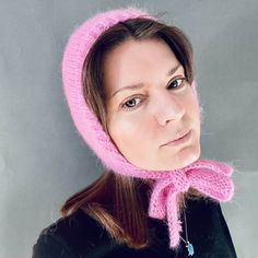 a woman wearing a pink knitted hat with a scarf around it's neck