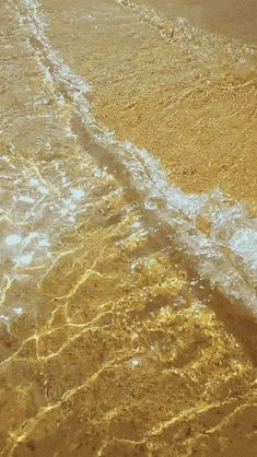 an airplane is flying low over the water at the edge of the beach, with waves coming in from the shore