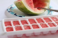 a watermelon and ice cubes on a plate next to a spoon with a piece of watermelon in it