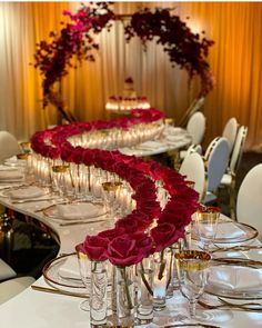 a long table is set with wine glasses and red roses on the centerpieces