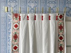 the curtains are hanging in front of blue wallpaper with red trimmings and pom poms