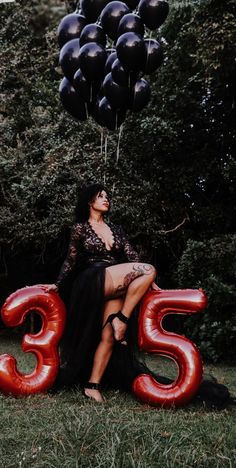 a woman sitting on top of a red number 35 balloon