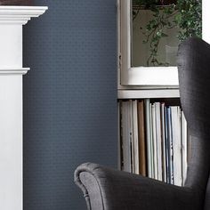 a grey chair sitting in front of a book shelf