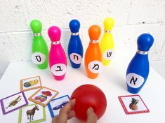 a child's hand is playing with colorful bowling pins and cards