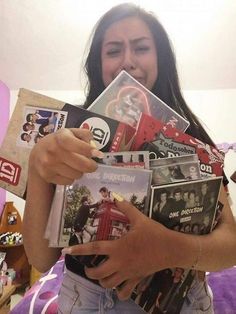 a woman holding up several cd's in her hands