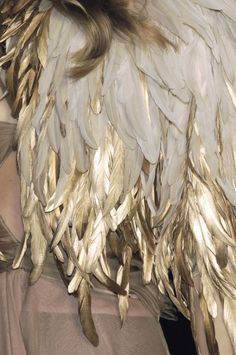 a close up of a woman's head with feathers on her hair and dress