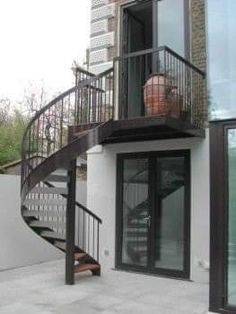 an outside view of a building with a metal stair case and glass door leading up to the second floor