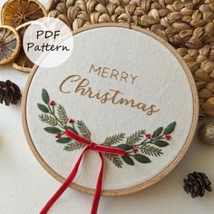 a cross - stitch pattern with the words merry christmas on it and pine cones around it