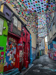 an alleyway with lots of colorful street art on the walls and ceiling above it