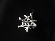 a white necklace is hanging on a black background with an ornament in the shape of a snowflake