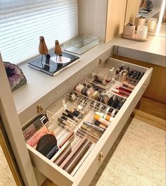 an open drawer in a bathroom with makeup and other items on the counter next to it