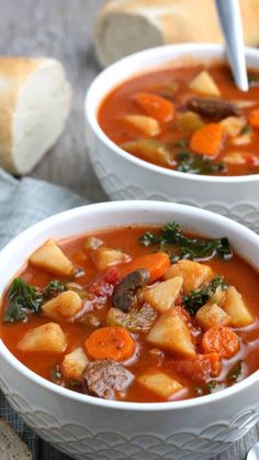 two bowls of vegetable soup with bread in the background