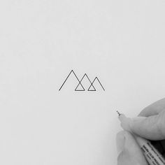 a person writing on paper with a pen and some type of triangle in the background