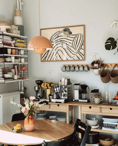 a dining room table and chairs in front of a wall with pictures on the wall