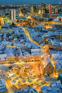 an aerial view of a city at night with snow on the ground and buildings lit up