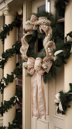 a wreath on the front door of a house decorated with pearls and ribbons for christmas