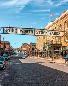 a street with cars parked on both sides and a sign that says fort worth stock yards