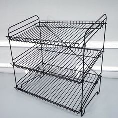 three tiered metal shelf with wheels on the bottom and bottom, against a white wall