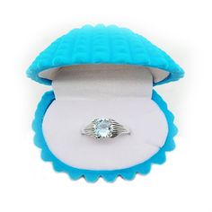 a ring in a blue case with a white diamond on the top and inside it