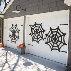 two garage doors decorated with spider webs and pumpkins