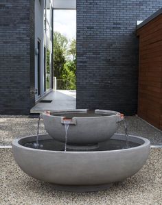 an outdoor fountain with water coming out of it's sides in front of a brick building