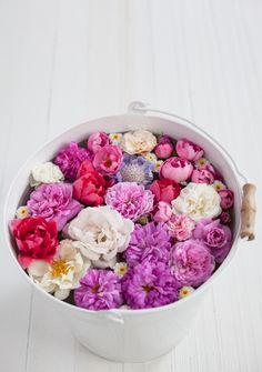 a white bucket filled with lots of different colored flowers