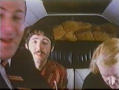 two men and a woman are sitting in the back seat of a car looking at something