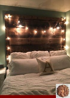 a bed that has some lights on the headboard and pillows in front of it