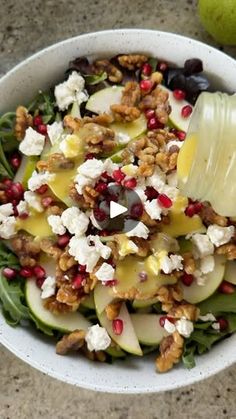 a white bowl filled with fruit and cheese on top of a table next to an apple