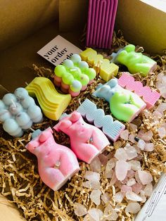 a box filled with lots of different shaped soaps on top of wood shaving