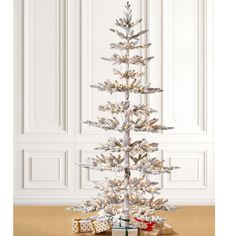 a small white christmas tree with presents under it on the floor in front of a wall