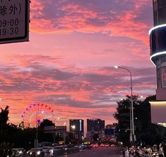 the sky is pink and purple as people are walking down the street