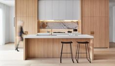 two stools in front of an island with marble counter top and wooden cabinetry