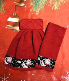 two red oven mitts sitting on top of a table next to a christmas tree