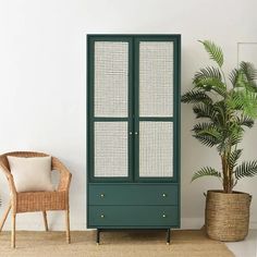 a green cabinet next to a wicker chair and potted plant