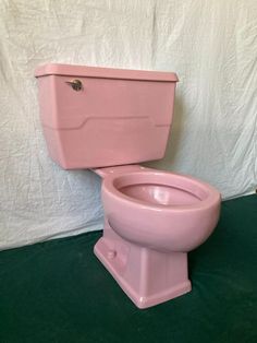 a pink toilet sitting on top of a green floor