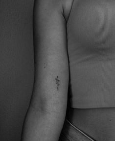 a black and white photo of a woman's arm with a small flower tattoo on it