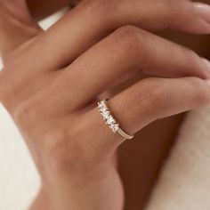 a woman's hand wearing a gold ring with three stones on the middle finger