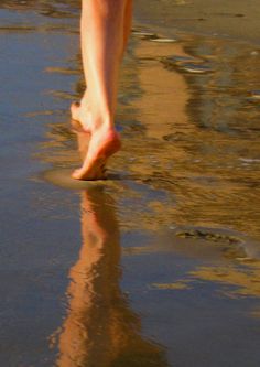 a person walking on the beach with their feet in the water