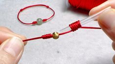 someone is making a string bracelet with red thread