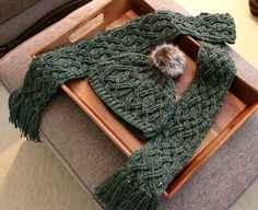 a green knitted scarf sitting on top of a wooden tray